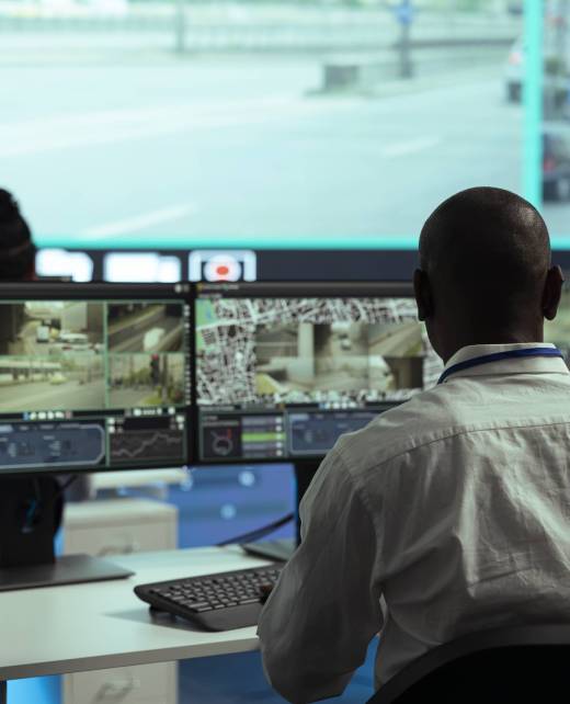 Observation room employee reviewing video surveillance footage to find illegal activity within urban traffic, big screen. African american man collecting data via CCTV radar system.
